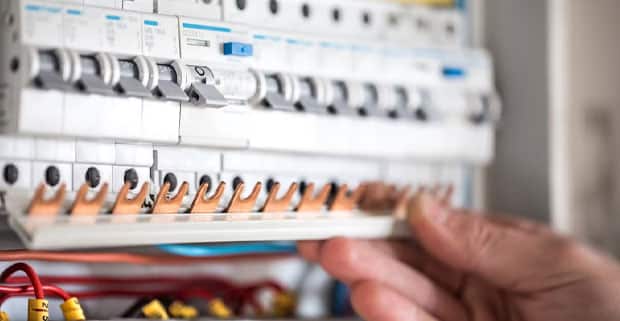 Electrical Technician Working In A Switchboard With Fuses — Electricians in Southport, QLD