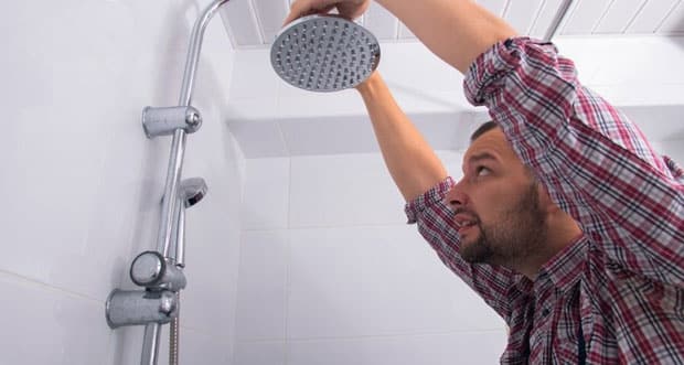 Man Repairing Shower Head On Bathroom — Plumbers in Helensvale, QLD