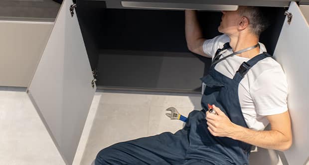 Top View Of Man Plumber In Overalls Fixing Breakdown Of Sink — Electricians in Robina, QLD