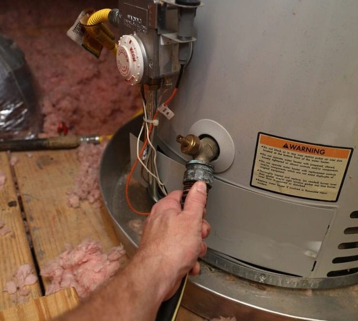 Hand Attaches Hose To Water Heater — Plumbers in Mermaid Waters, QLD